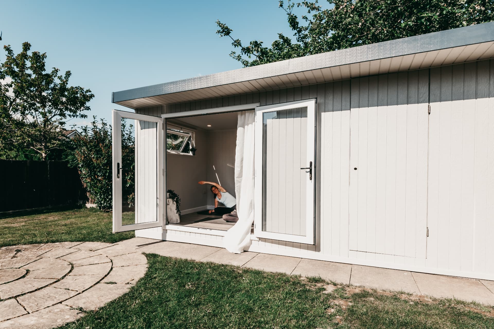 White garden yoga room with French doors open onto the lawn