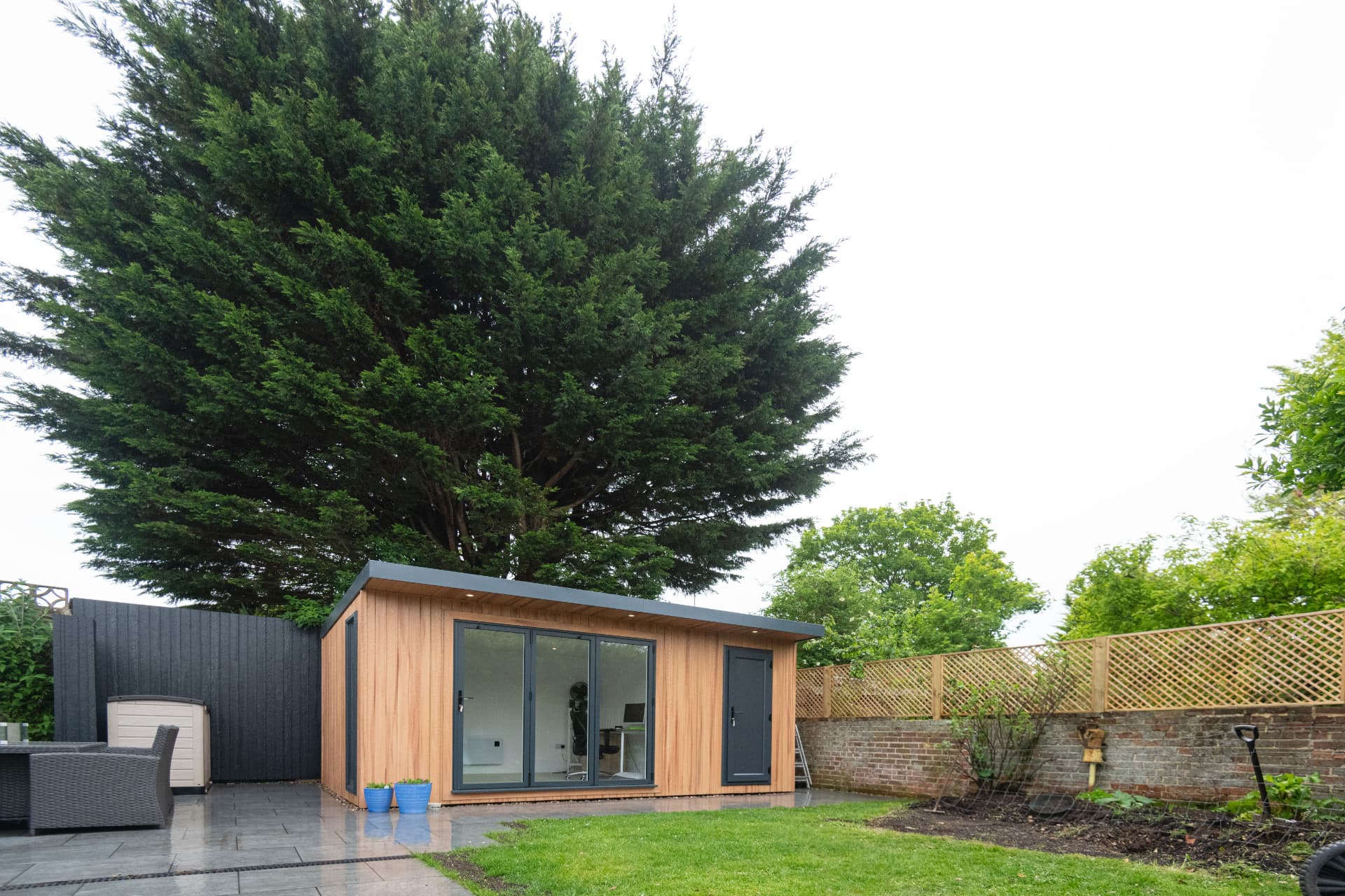 Cedar garden room set under a mature tree on a paved patio