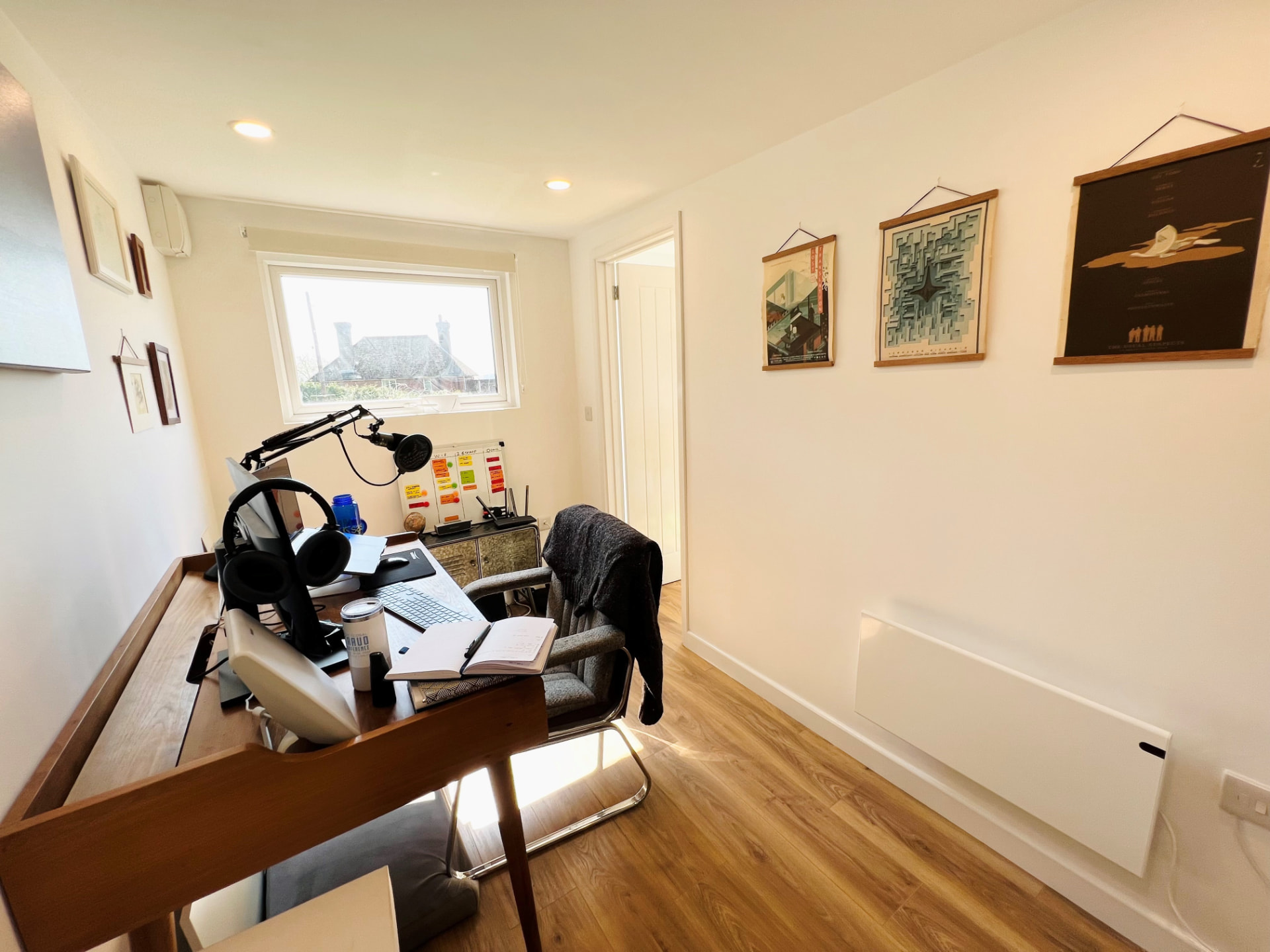 Garden room interior fitted out as a home office with desk, monitor and framed prints