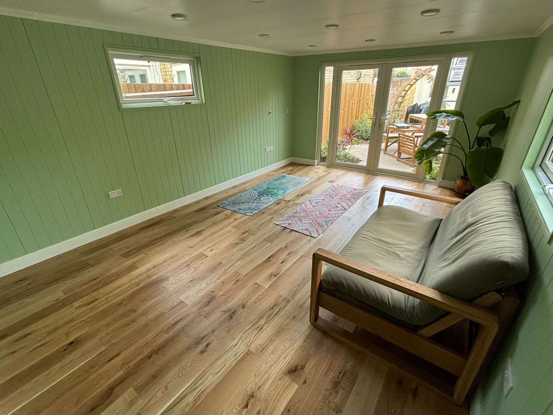 Astana Range garden room interior in sage green with oak flooring, yoga mats and French doors