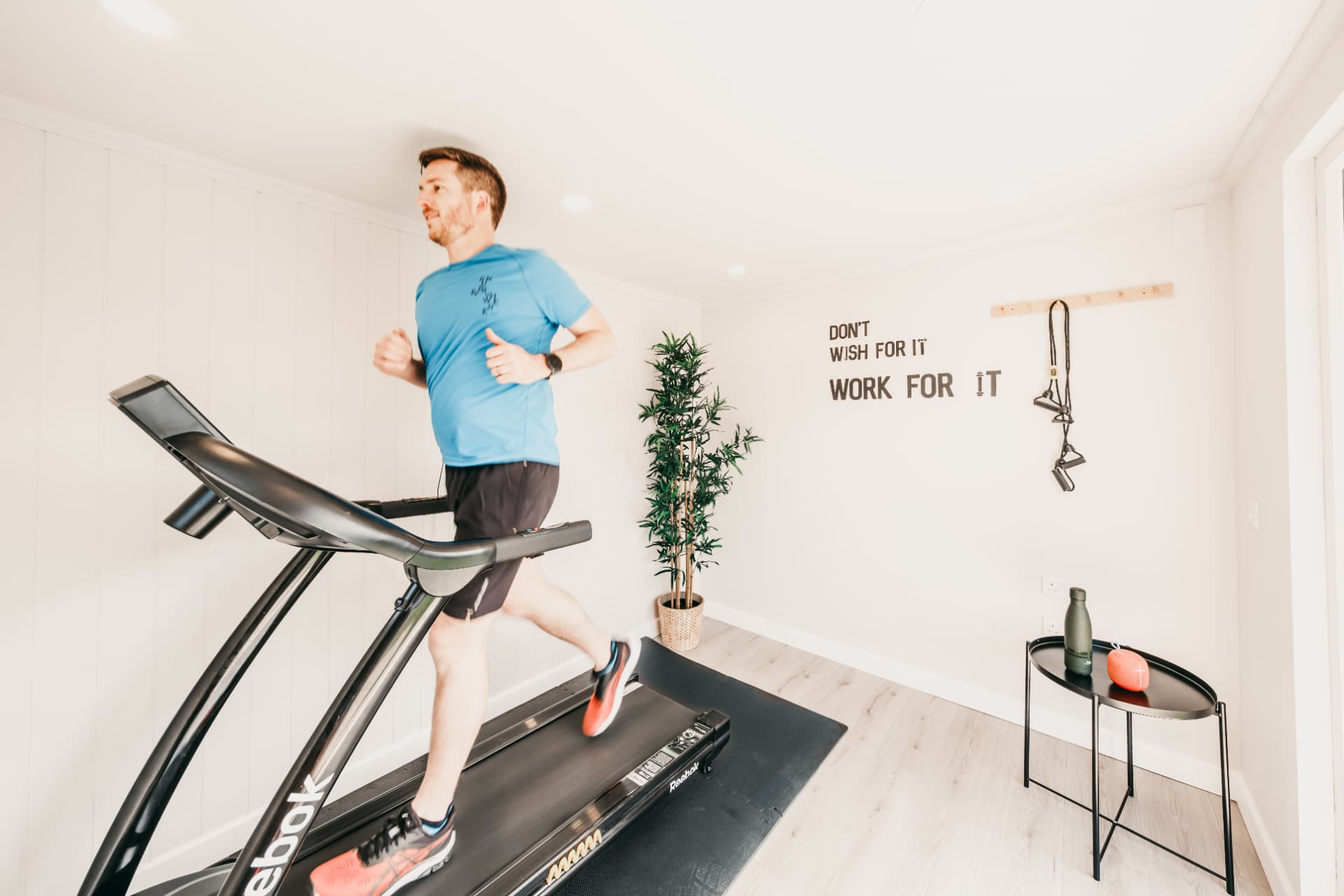 Man running on a treadmill inside a bright white garden gym