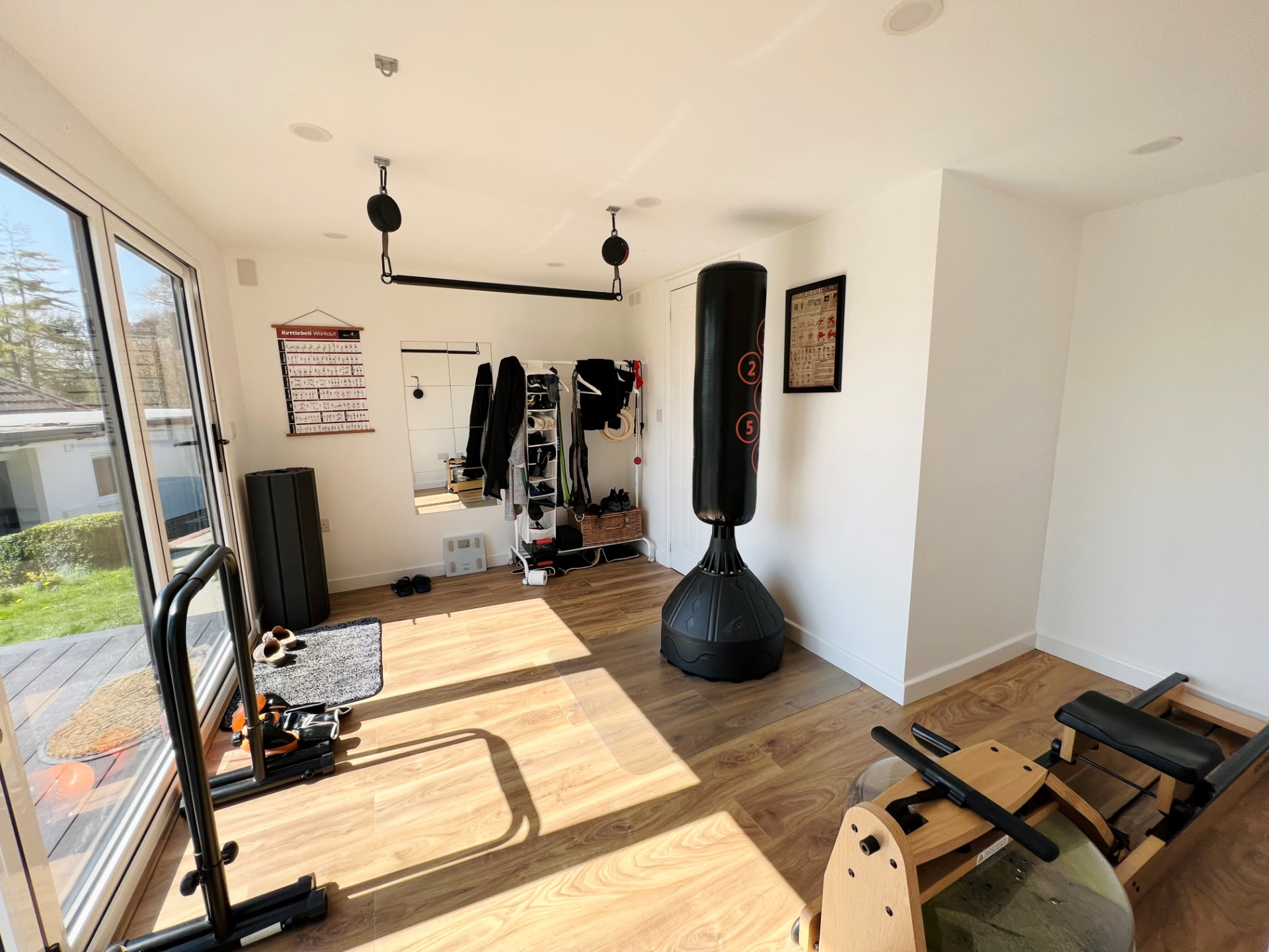 Bright garden gym interior with rowing machine, free-standing punchbag and storage
