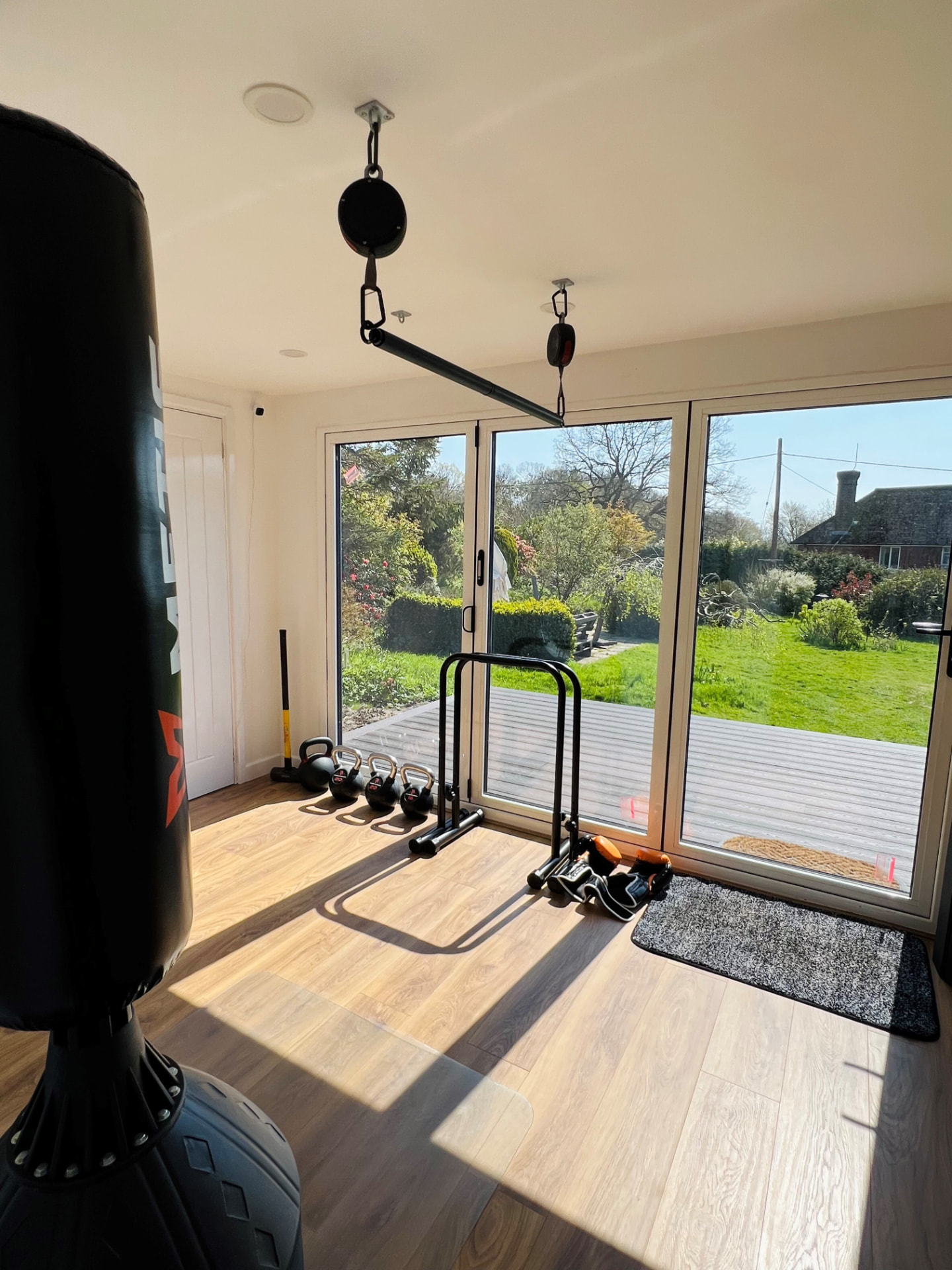 Garden gym interior with punchbag, kettlebells and sliding doors onto the garden