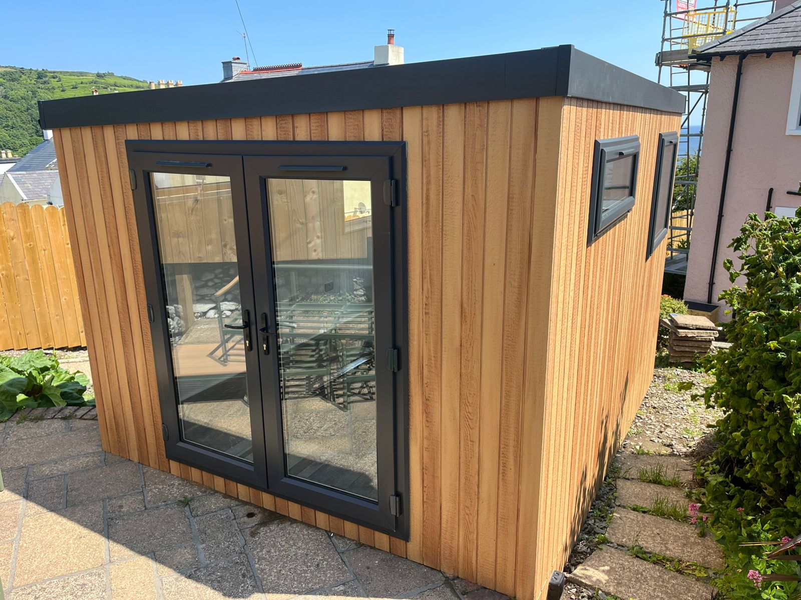 Astana Range garden room with no roof overhang, clad in Cedar ToughWood with anthracite French doors