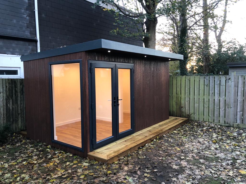 Troughwood garden room lit from inside with a decked entrance