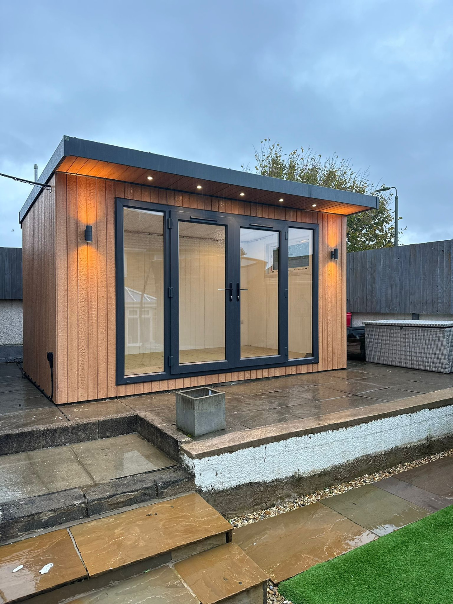 4.2m x 2.6m Signature SIPs garden room in ToughWood Cedar lit at dusk