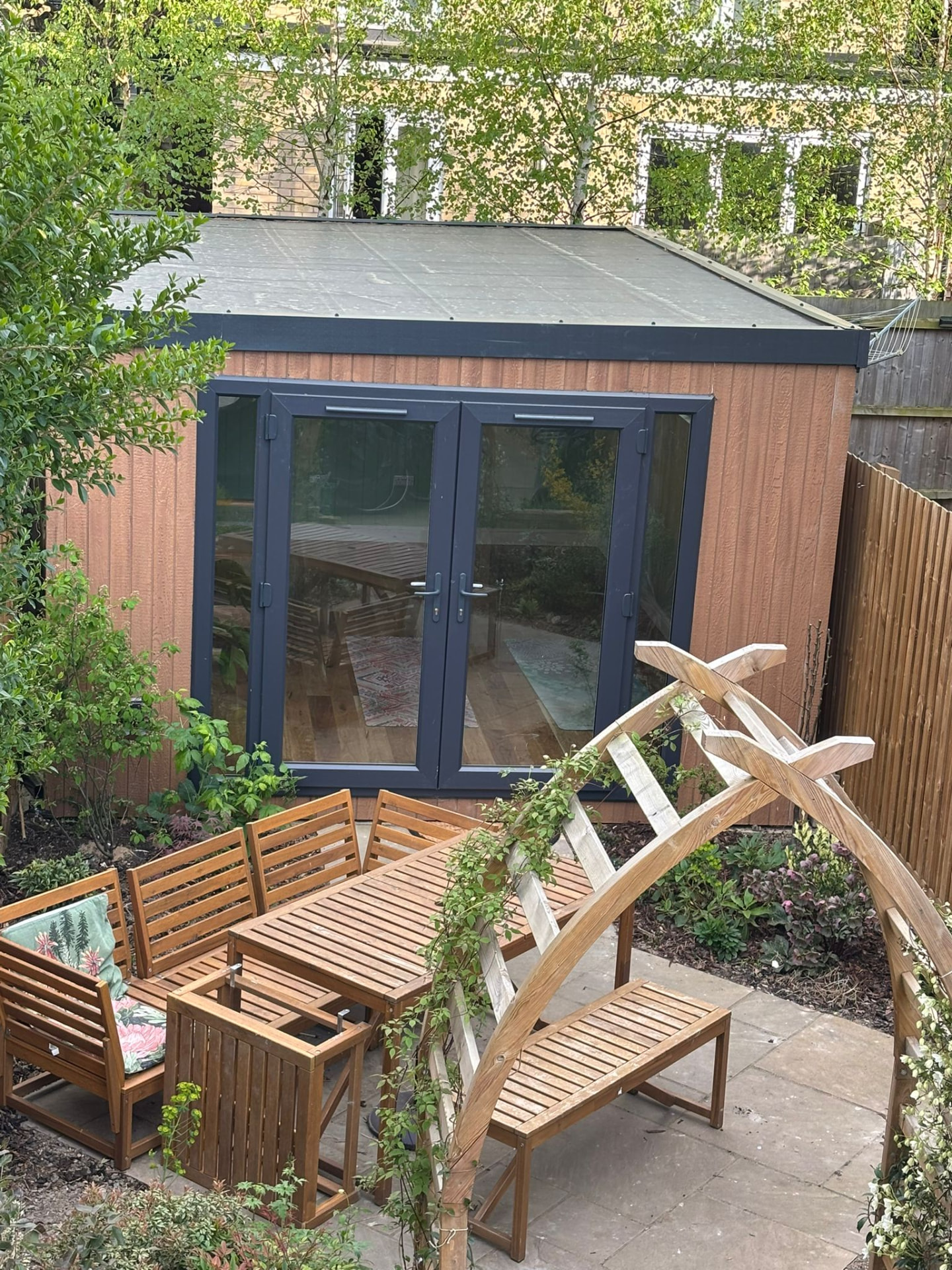Compact garden room with anthracite French doors overlooking a patio dining area
