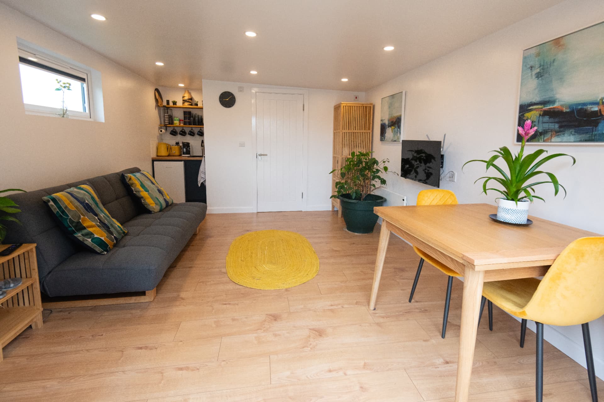 Open-plan garden room living space with sofa bed, kitchenette and dining table
