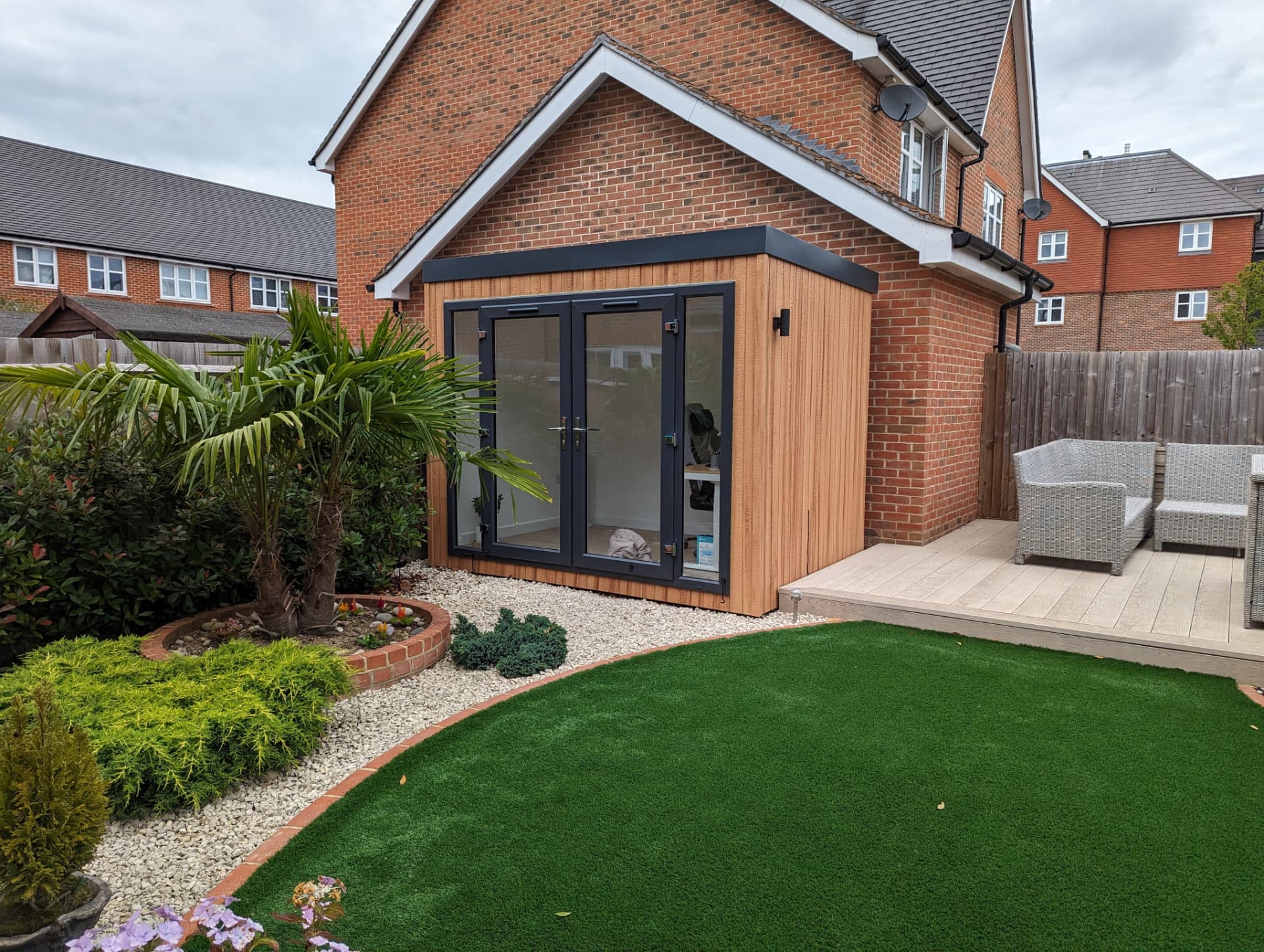Compact Astana Range Cedar garden office tucked beside the house on a landscaped patio