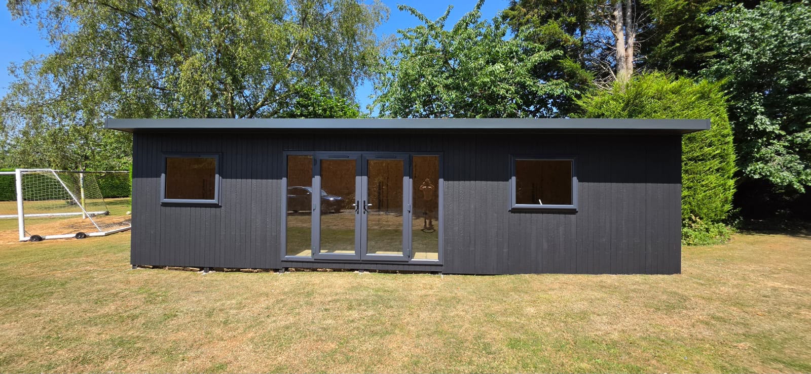 Wide Granite ToughWood garden room with French doors and twin windows on a lawn