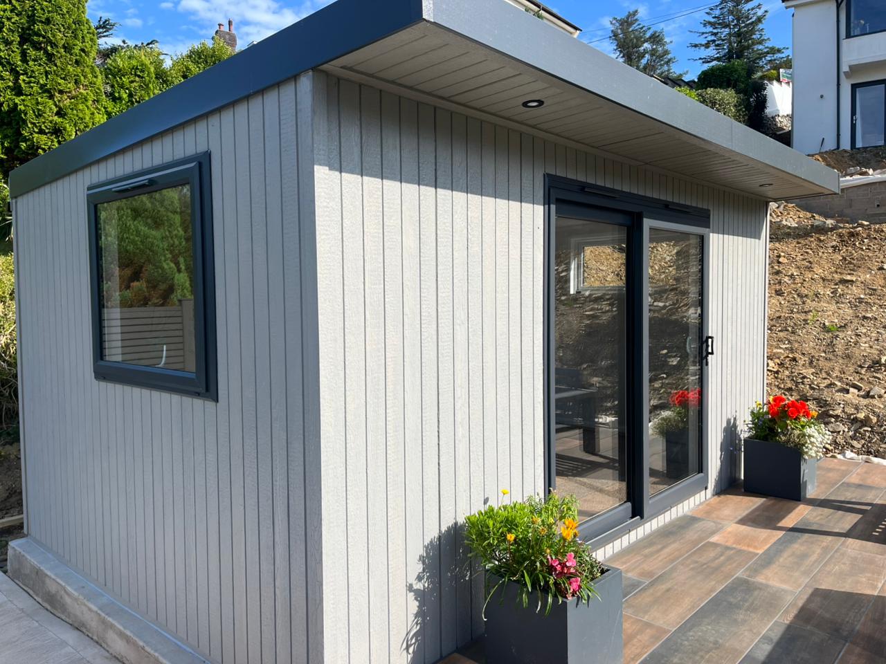 Silver Birch ToughWood garden room with sliding doors on a tiled patio