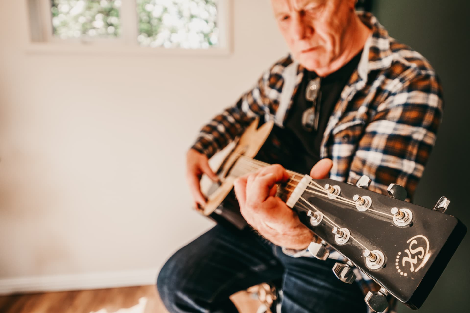 Close-up of a guitarist playing acoustic guitar in a garden music room