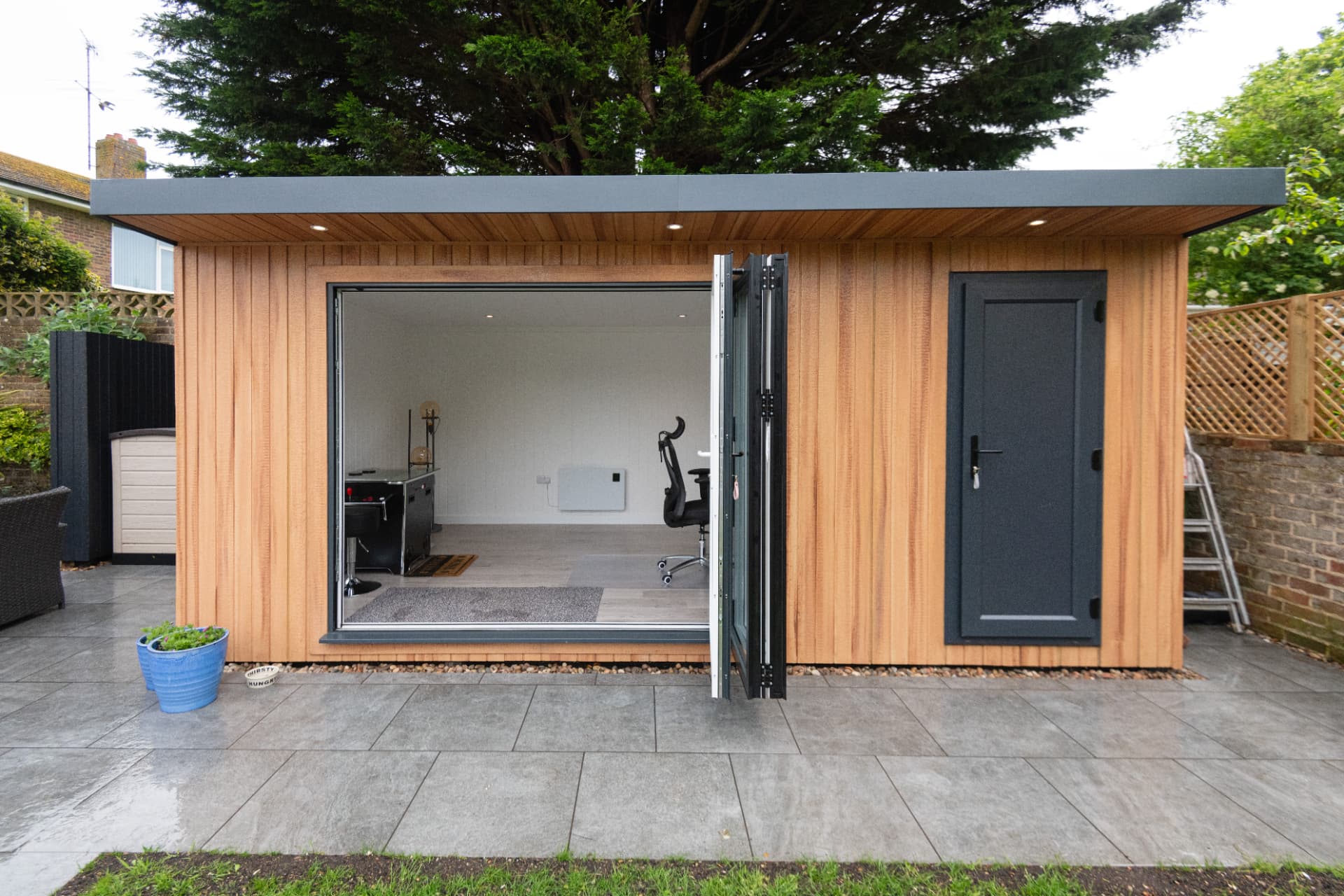 Cedar garden room with bifold doors folded open onto the patio
