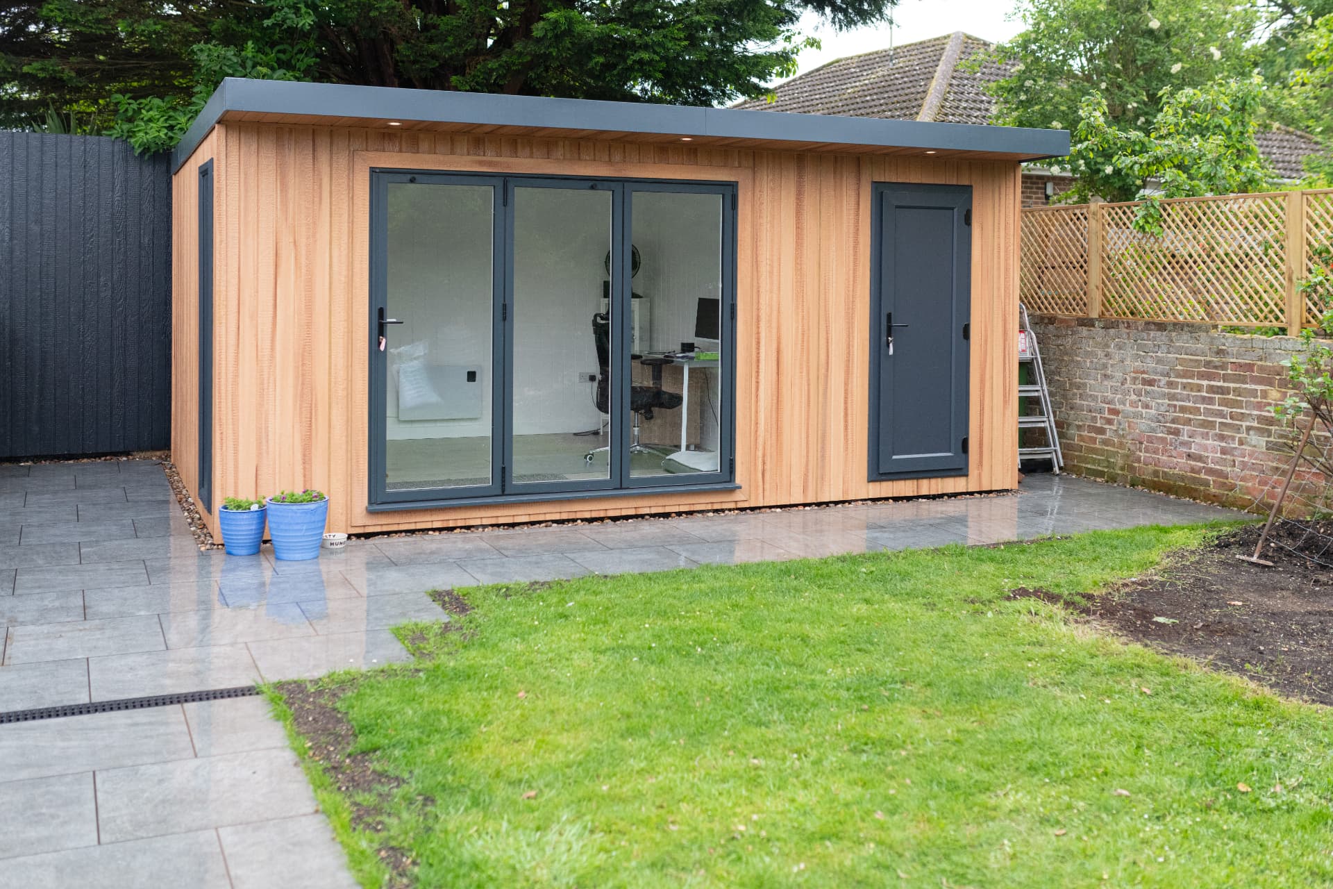 Cedar clad garden room with bifold doors and a separate storage door