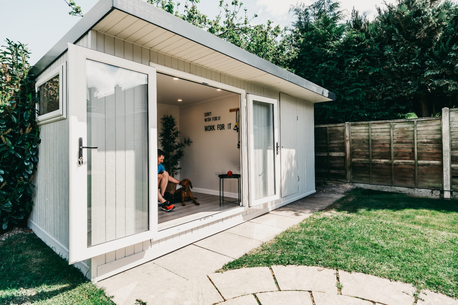 Light grey garden gym with sliding doors open onto a paved patio