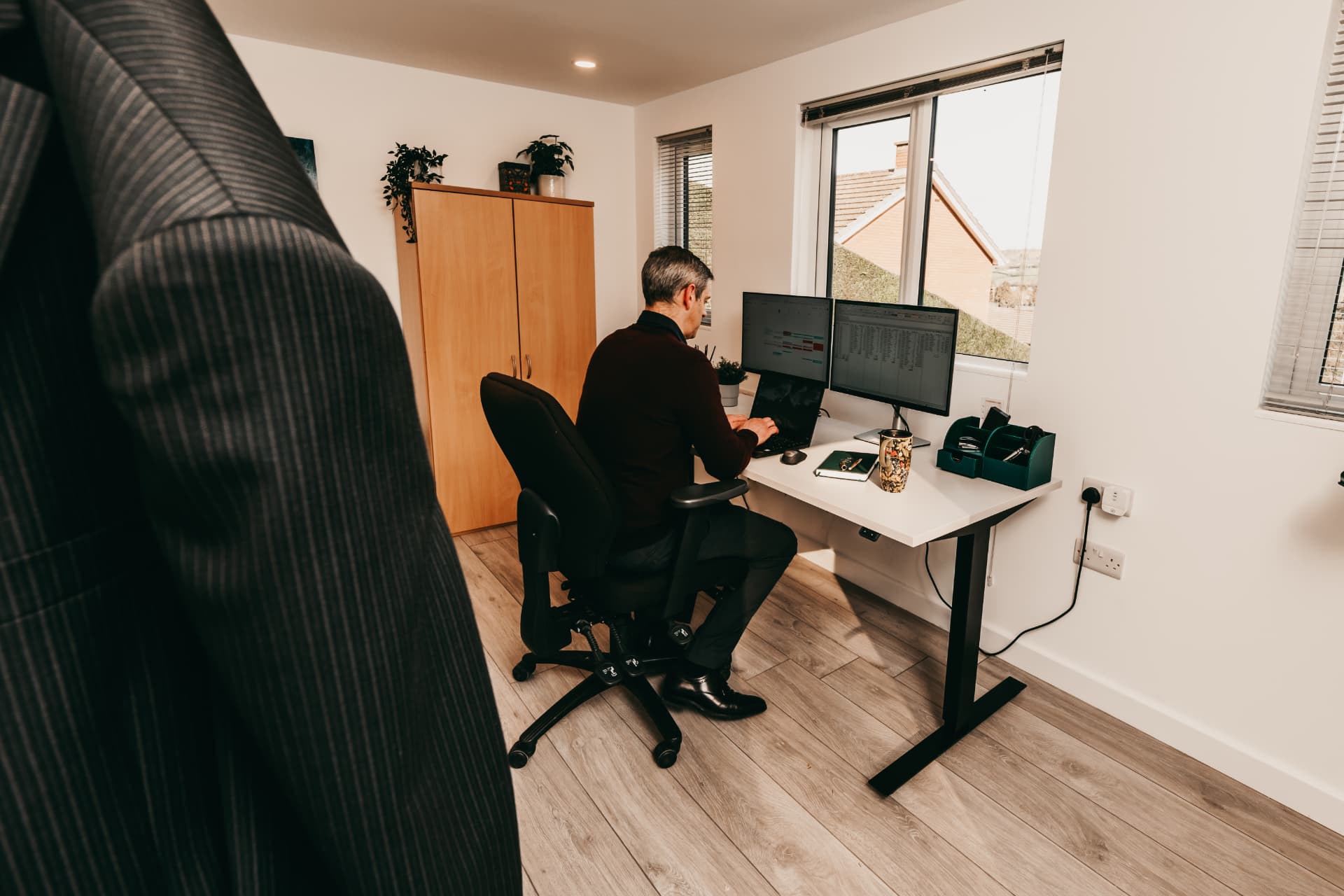 Garden office with a sit-stand desk, twin monitors and storage cupboard