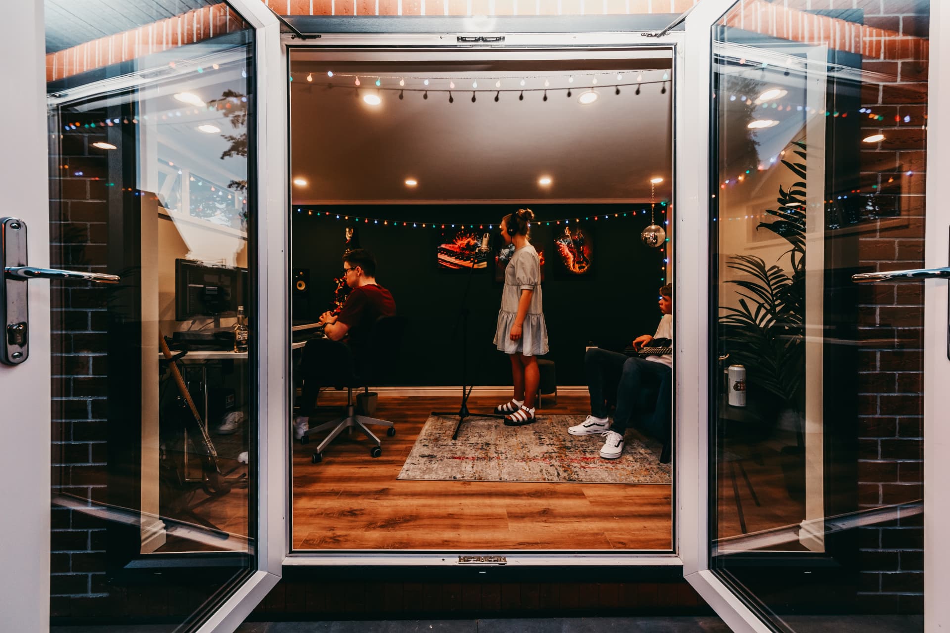Band recording in a garden music studio at night, seen through open French doors