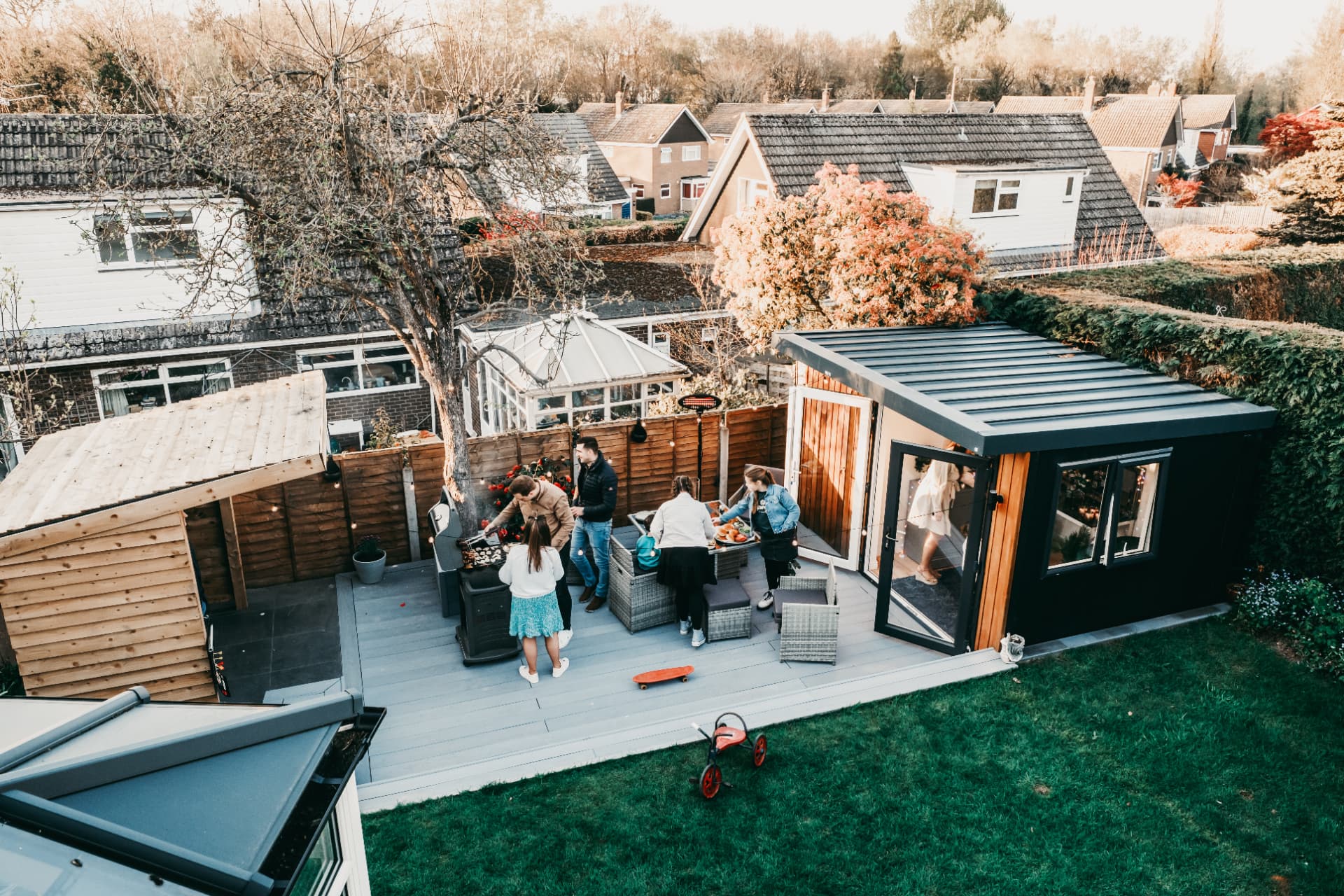 Aerial view of a family barbecue on the deck beside an anthracite and cedar garden room