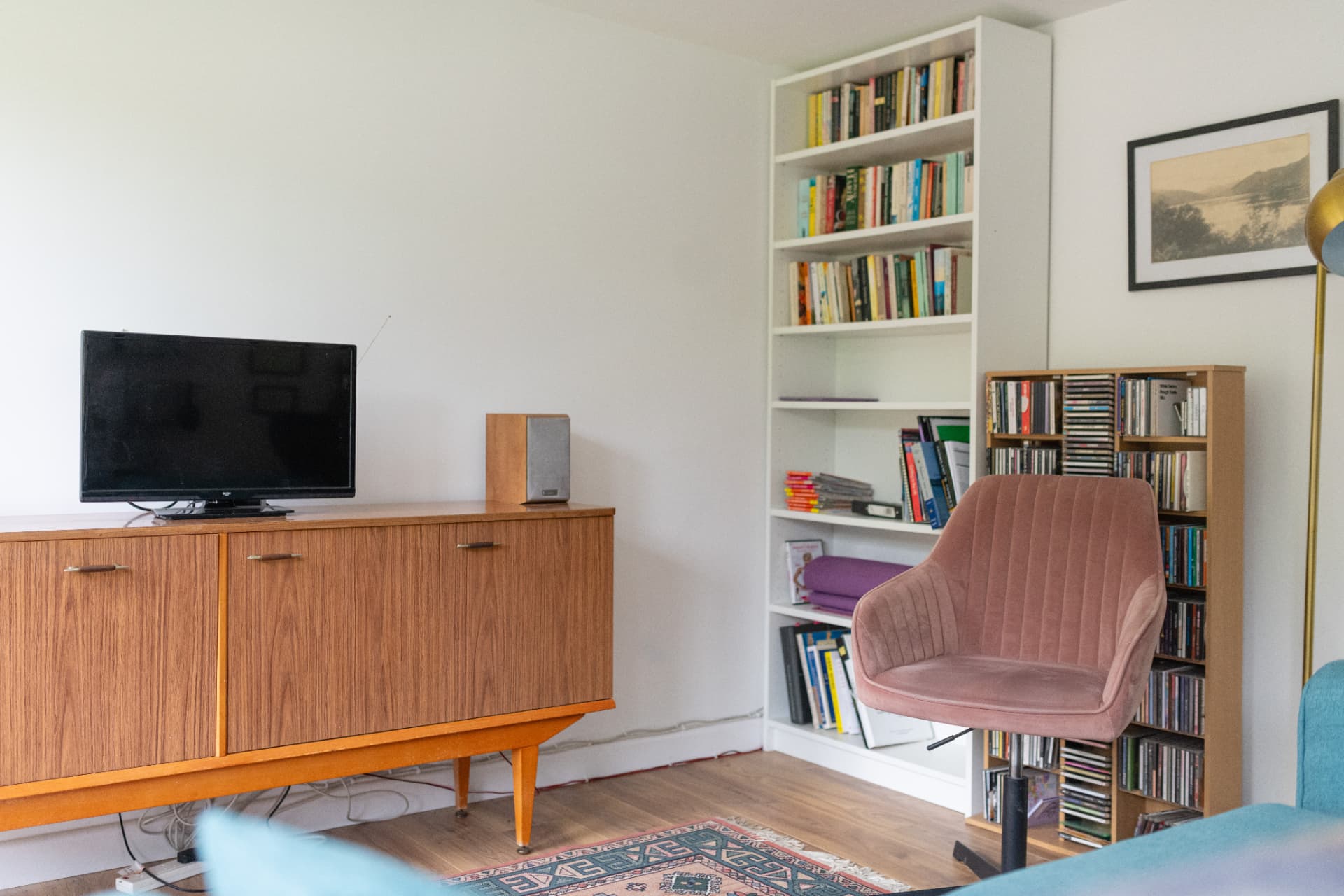 Garden room living area with a sideboard, TV, bookcases and armchair