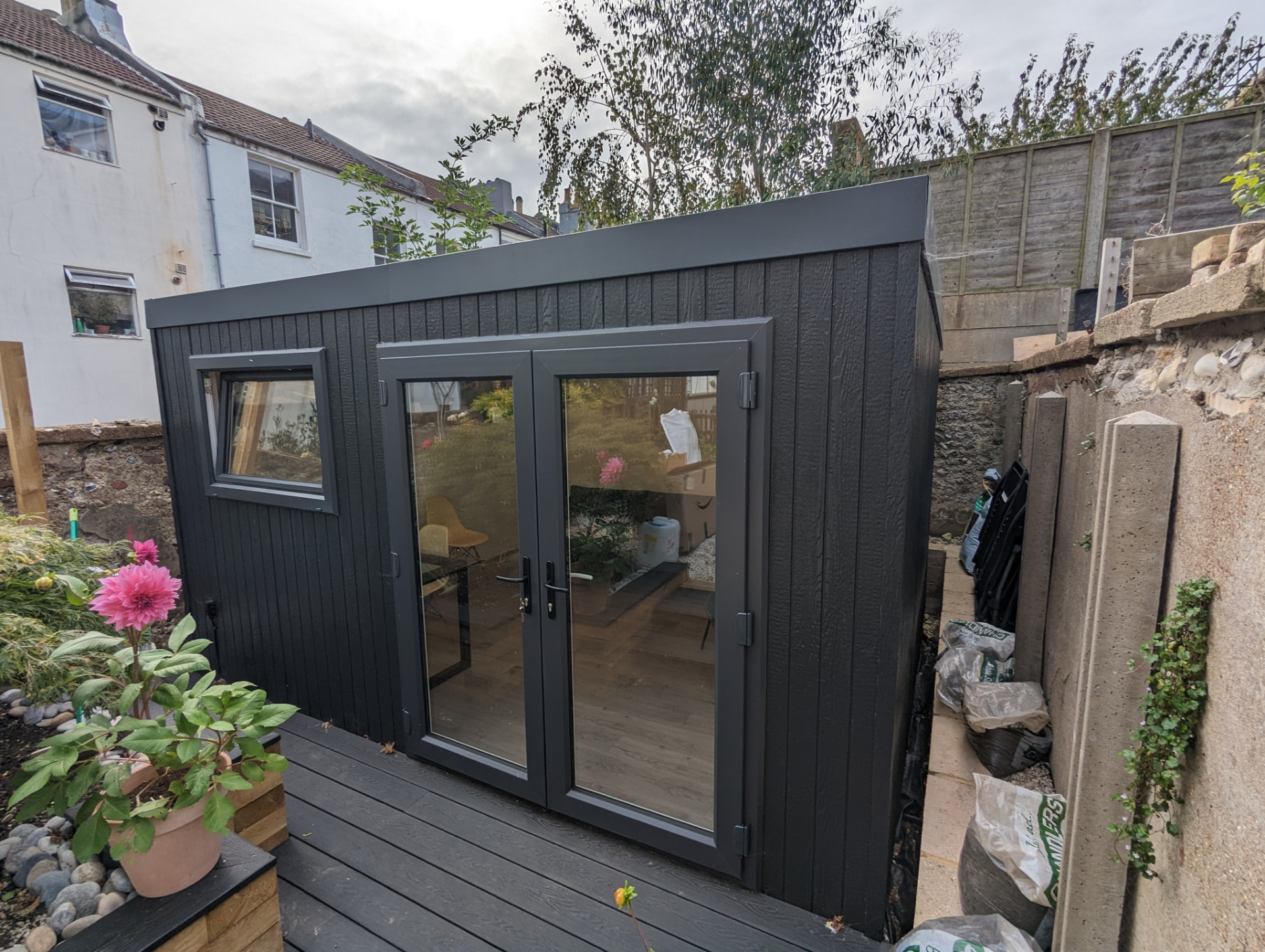Anthracite clad garden room with matching French doors and composite decking in a courtyard garden