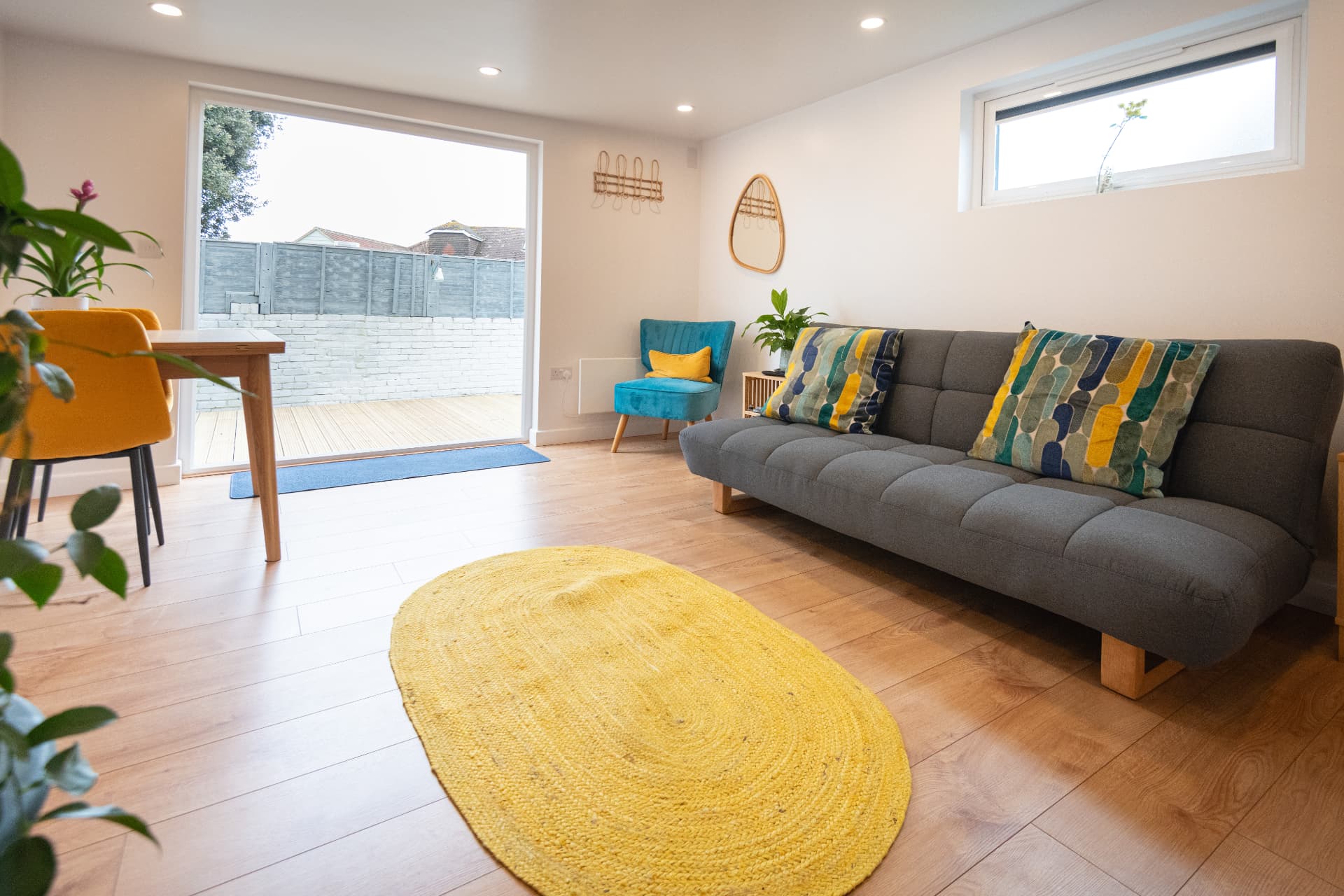 Garden room lounge with a grey sofa bed and sliding doors open onto the deck