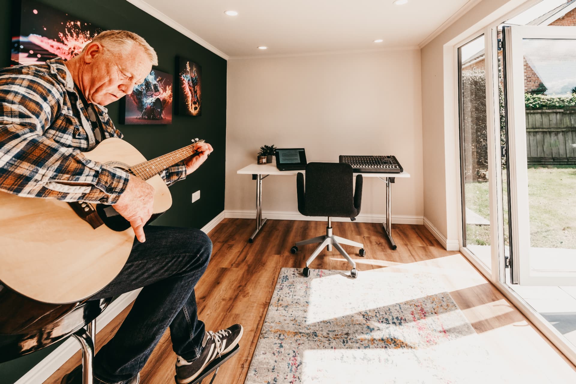 Garden music room with a dark feature wall, guitarist on a stool and mixing desk