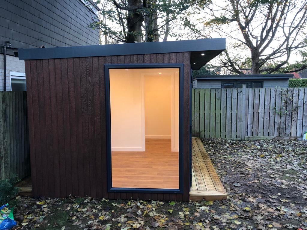Troughwood garden room at dusk with a full-height picture window